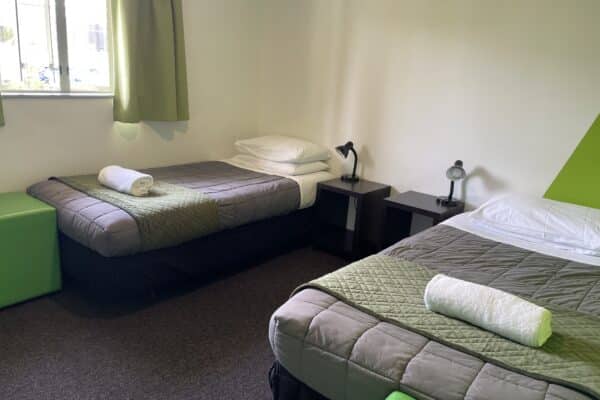 Twin room with two single beds, side tables, power points, and lamps at Accents YHA Hostel Nelson