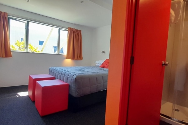 Sunny room featuring a queen bed with stylish ensuite bathroom, modern ambiance, bedside tables, and Smart TV